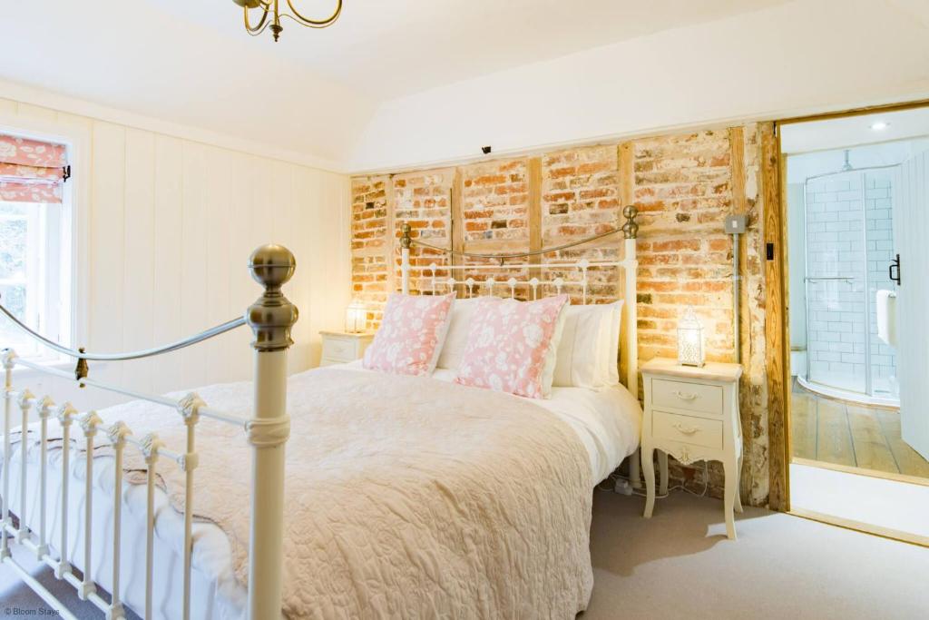 - une chambre avec un lit et un mur en briques dans l'établissement Oast Barn Cottage by Bloom Stays, à Faversham