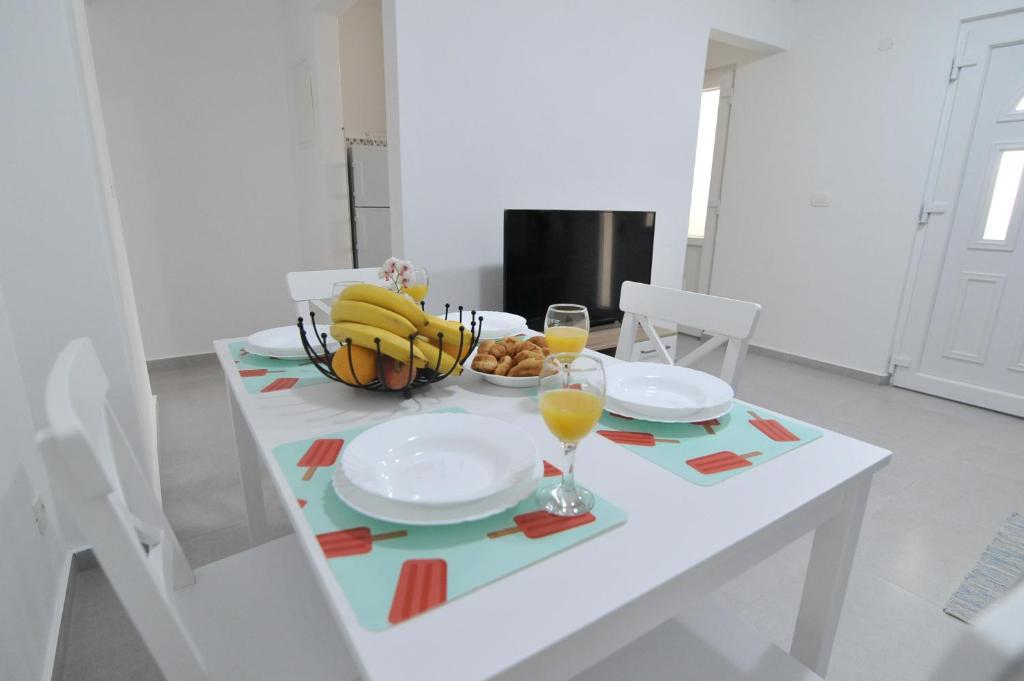 - une table blanche avec un bol de bananes et des verres de jus d'orange dans l'établissement Sandy beach apartments, à Ljubač