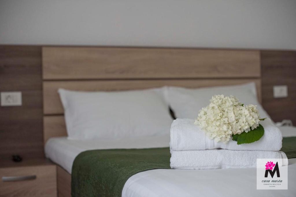 a bed with white towels and a bouquet of flowers at CasaMarta in Baile Felix