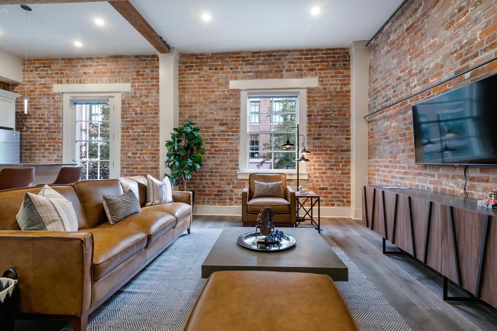 a living room with brown furniture and a brick wall at The St John in New Orleans