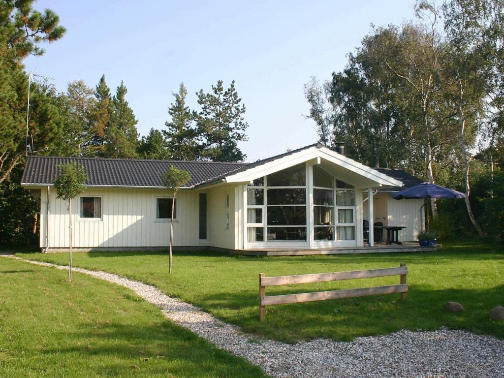 ein weißes Haus mit einer Bank davor in der Unterkunft 10 person holiday home in Gr sted in Udsholt Sand