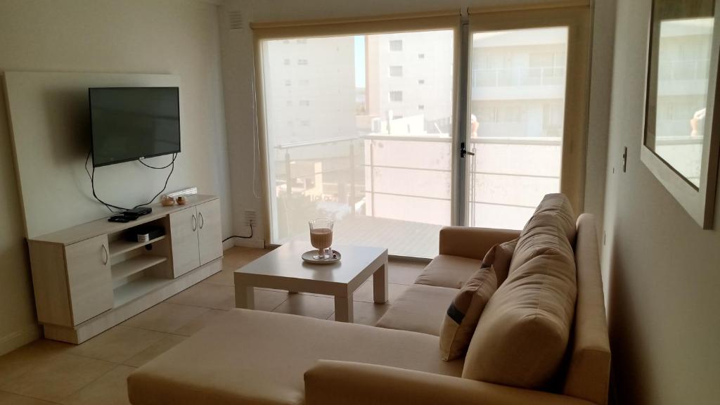 uma sala de estar com um sofá e uma televisão em Deptos MORE II em Puerto Madryn