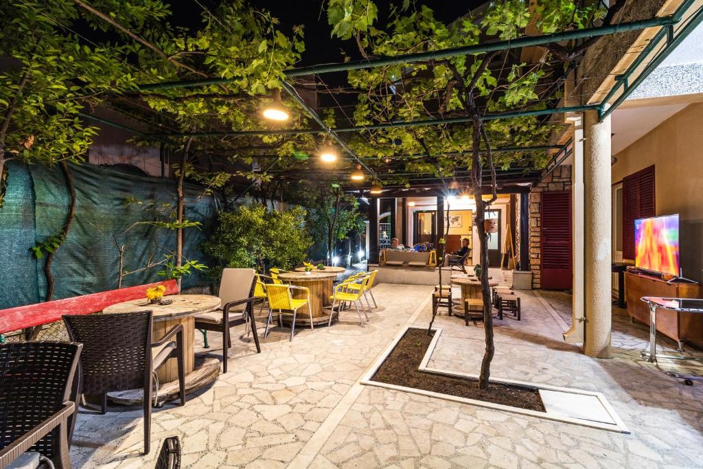 an outdoor patio with tables and chairs and trees at Hostel Budva in Budva