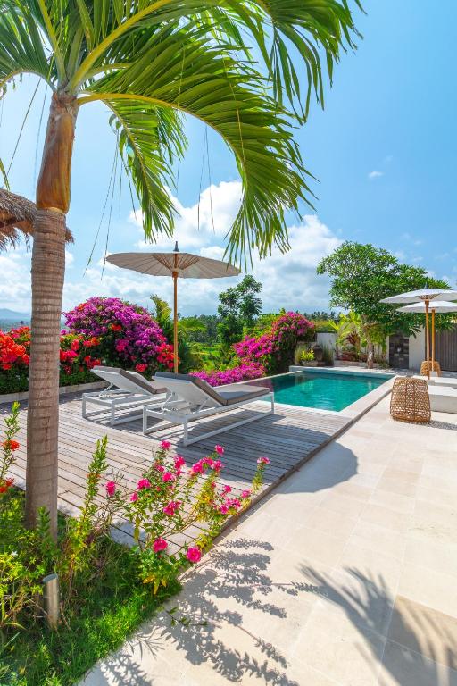 a swimming pool with a palm tree and flowers at Villa Butterflydream in Karangasem