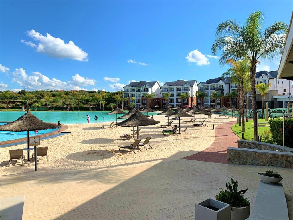 einen Strand mit Stühlen und Sonnenschirmen sowie einen Pool in der Unterkunft Penthouse 172 at The Blyde Crystal Lagoon in Pretoria