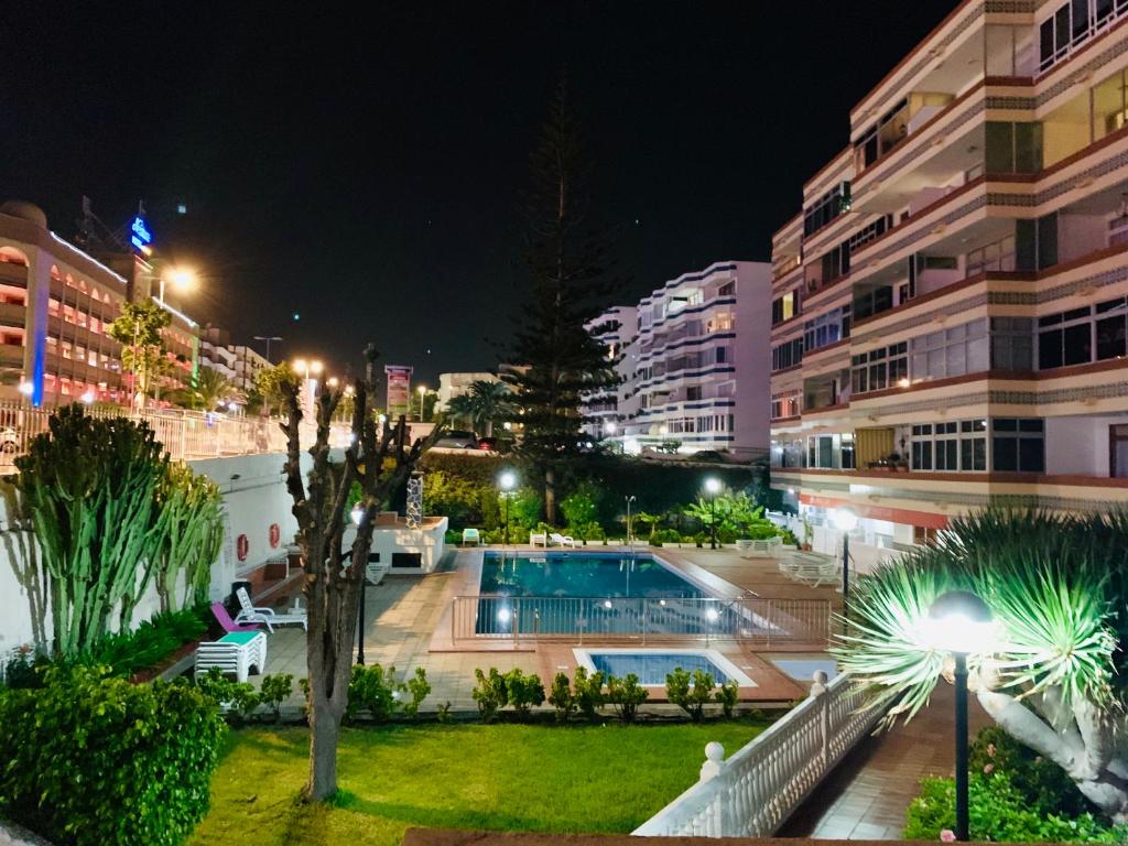 una ciudad por la noche con una piscina y edificios en Calm, Cosy and Bright apartment renovated in playa del ingles- WiFi free, en Playa del Inglés