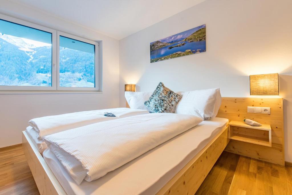 a bedroom with a large white bed with two windows at Apart Blasblei in Sankt Gallenkirch