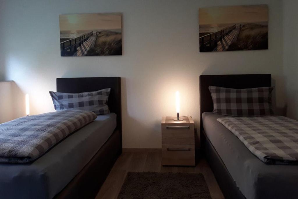 a bedroom with two beds and a night stand with a lamp at C&C Gästehaus Bückeburg in Bückeburg