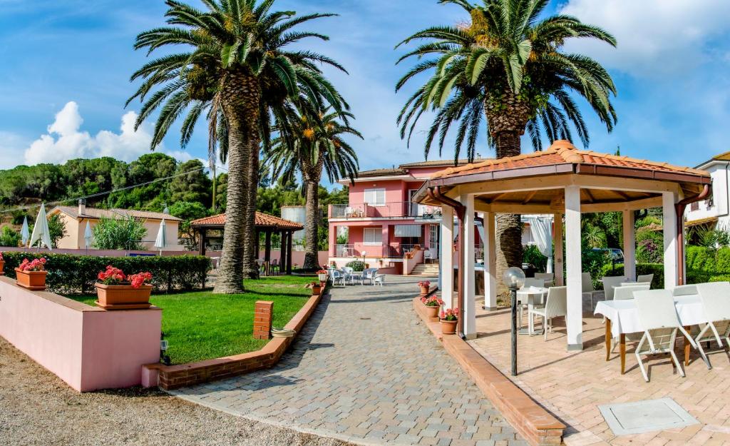 un patio con cenador y palmeras en Hotel Villa Rosa, en Porto Azzurro