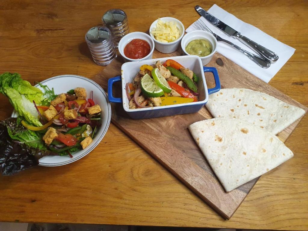 a wooden table with a tray of food with a salad and a bowl of food at Kintrae B&B in Buckie