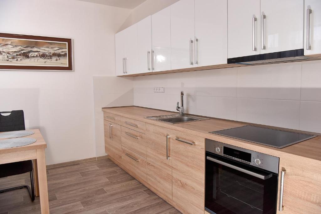 uma cozinha com armários brancos, um lavatório e um fogão em Apartmán Lydie em Karolinka