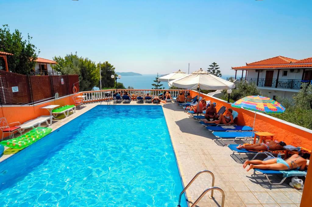 a swimming pool with people sitting on chairs next to it at elenis village in Achladies