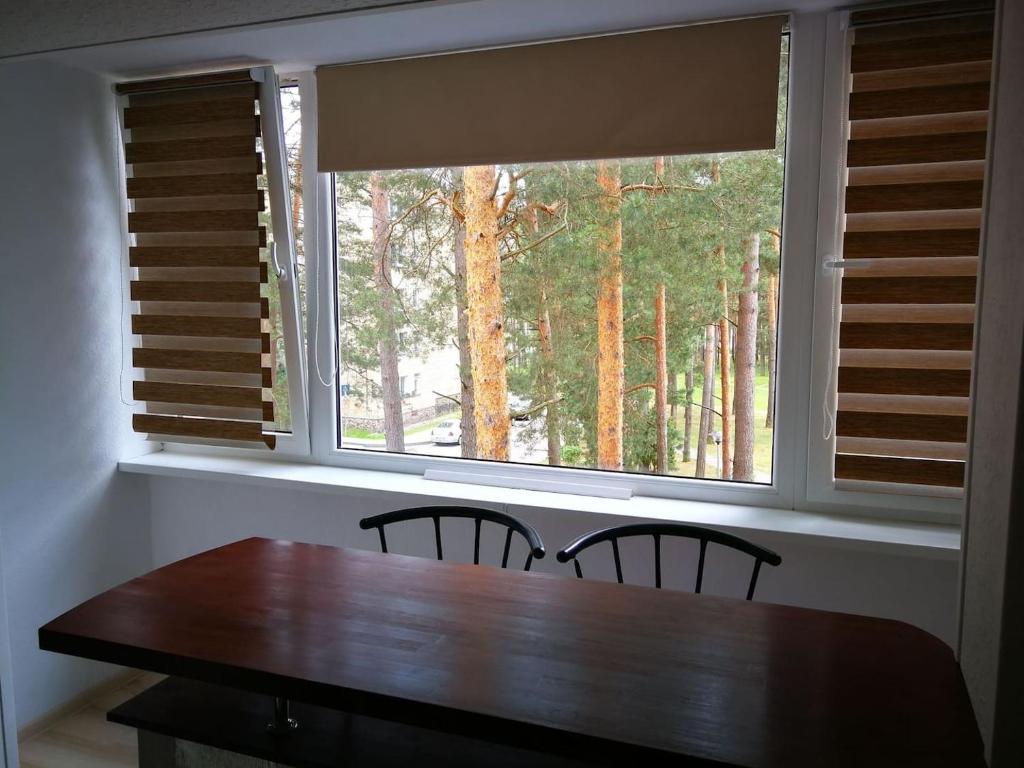 mesa de comedor con 2 sillas y ventana grande en Light one room apartment, en Visaginas