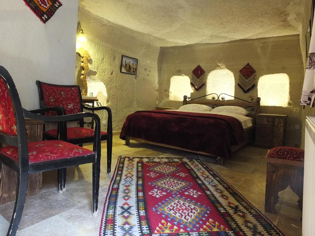 1 dormitorio con 1 cama, 1 silla y 1 alfombra en Anatolia cave hotel Pension en Göreme