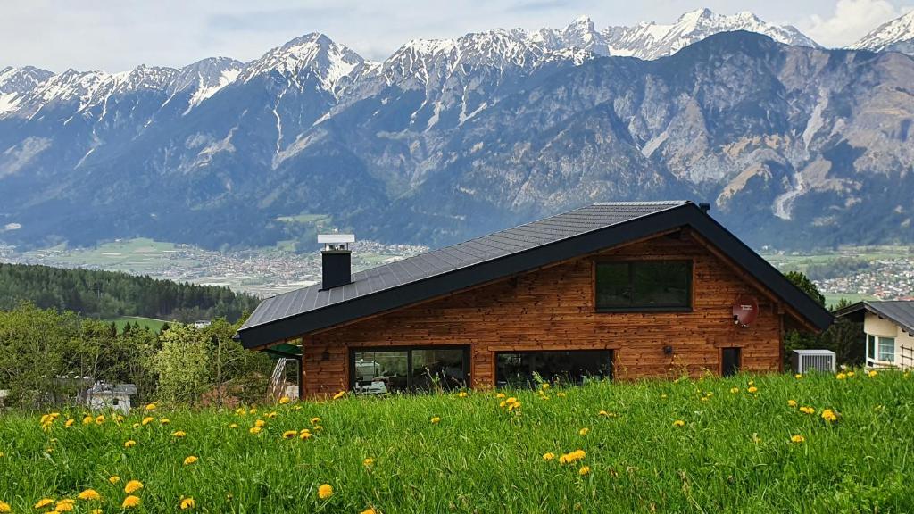 a log cabin in a field with mountains in the background at Gschwendtalm Tirol - Luxus-Apartment für Ihre Auszeit in Tulfes