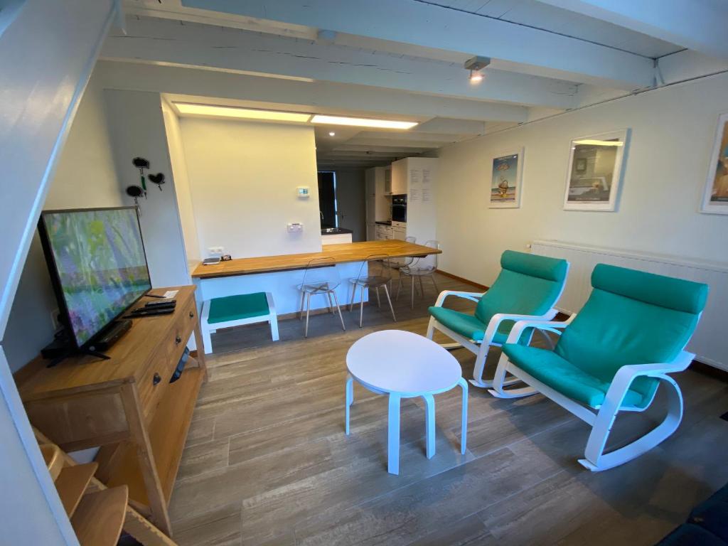 una sala de espera con sillas verdes y una mesa en Barkas 23, en Nieuwpoort