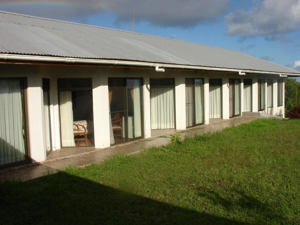 a white building with a grassy yard in front of it at Hotel Victoria in Hanga Roa