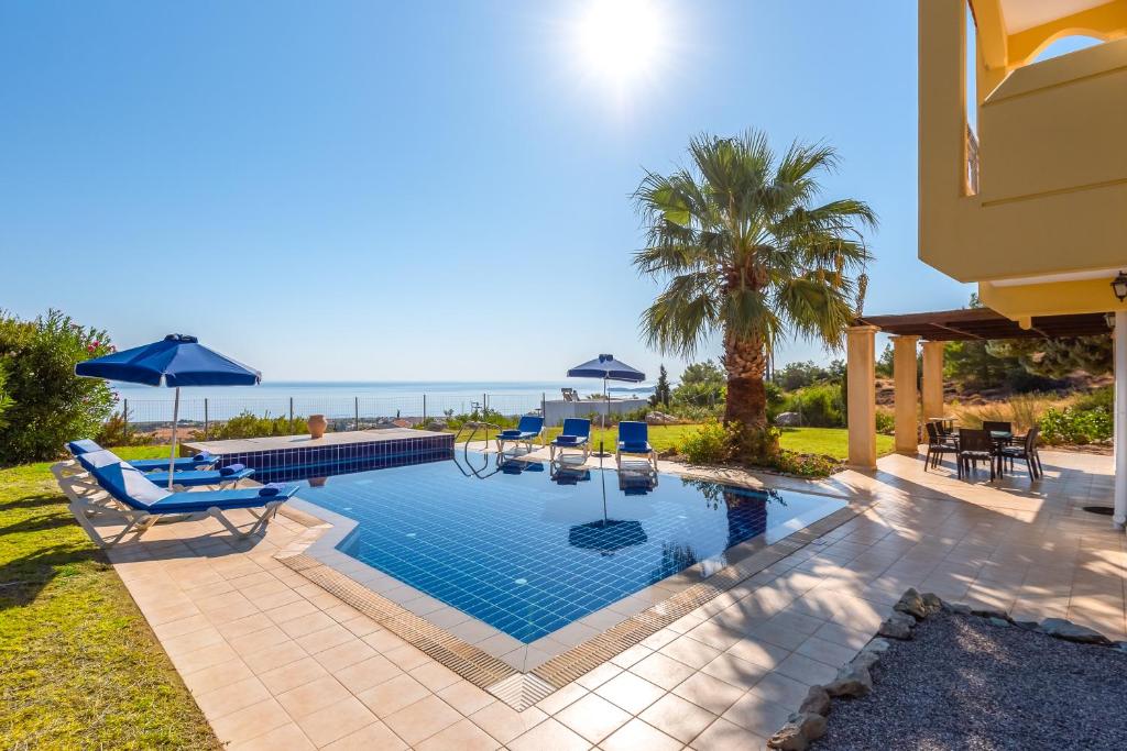basen z leżakami i parasolami oraz ocean w obiekcie Villa Irene, Amazing views, Lindos 10 mins, Beach 4 mins w mieście Kalathos