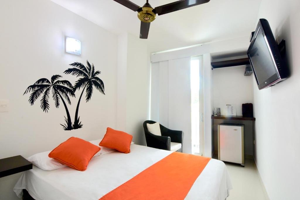Hotel Florida Sincelejo في سينسليخو: غرفة نوم مع سرير مع وسائد برتقالية وتلفزيون