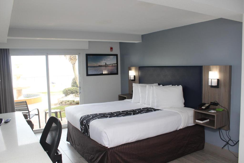 a hotel room with a large bed and a balcony at La Quinta by Wyndham Oceanfront Daytona Beach in Daytona Beach