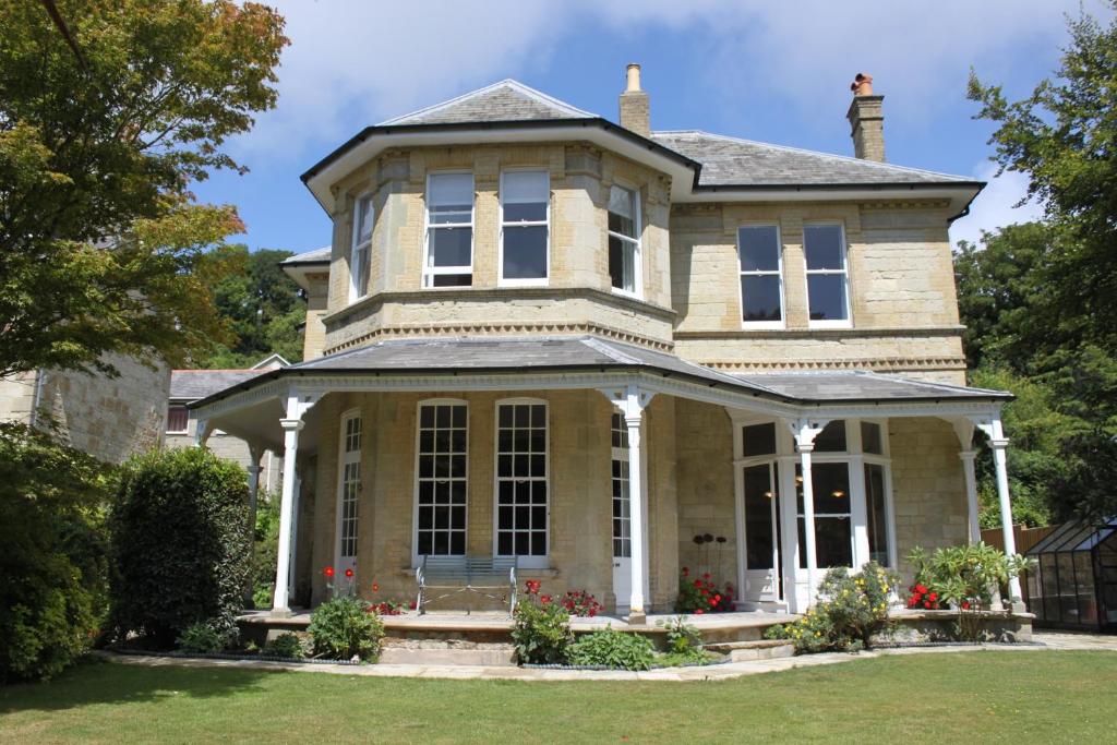 uma casa antiga com um grande alpendre frontal em Clarence House Apartments em Ventnor