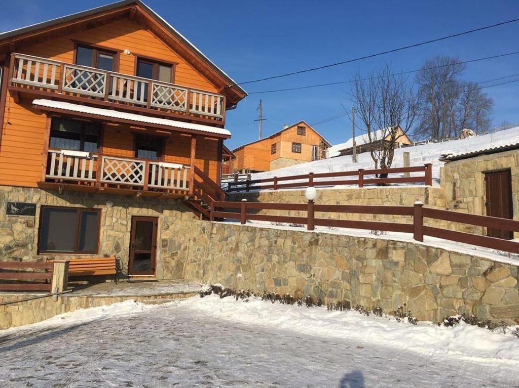 una gran casa de madera con una pared de piedra en Вовкаль en Yablunytsya