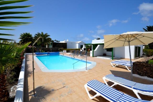 a swimming pool with two chairs and an umbrella at Terracitas 28 & 27 in Playa Blanca