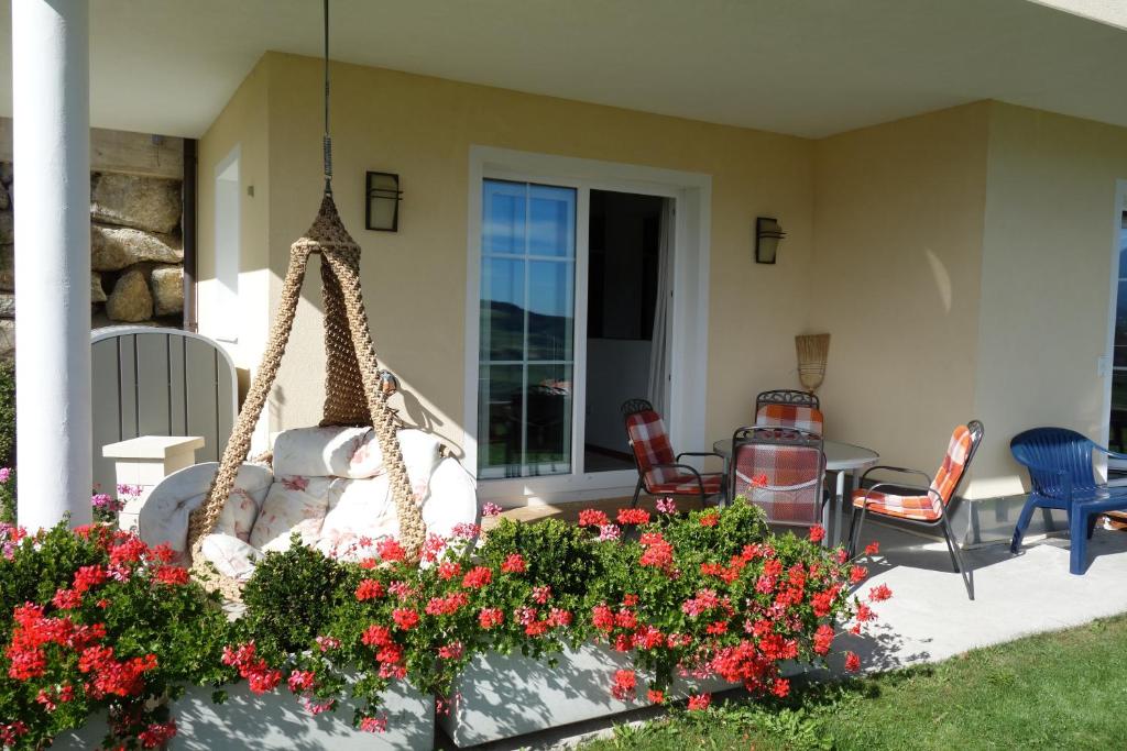 un porche con sillas, un columpio y flores en Appartment Schwarzenauer, en Mutters