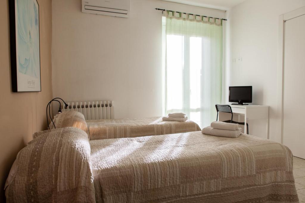 - une chambre avec 2 lits, une télévision et une fenêtre dans l'établissement Il Verde Pino, à Ancône