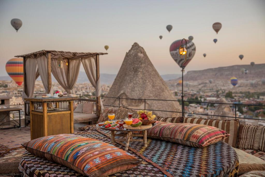 a balcony with couches and a table and hot air balloons at Divan Cave House in Göreme