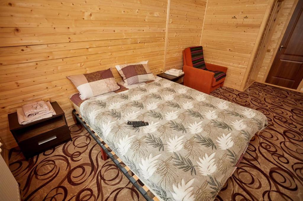 a bedroom with a large bed and a chair at Villa Na uzlissi in Migovo