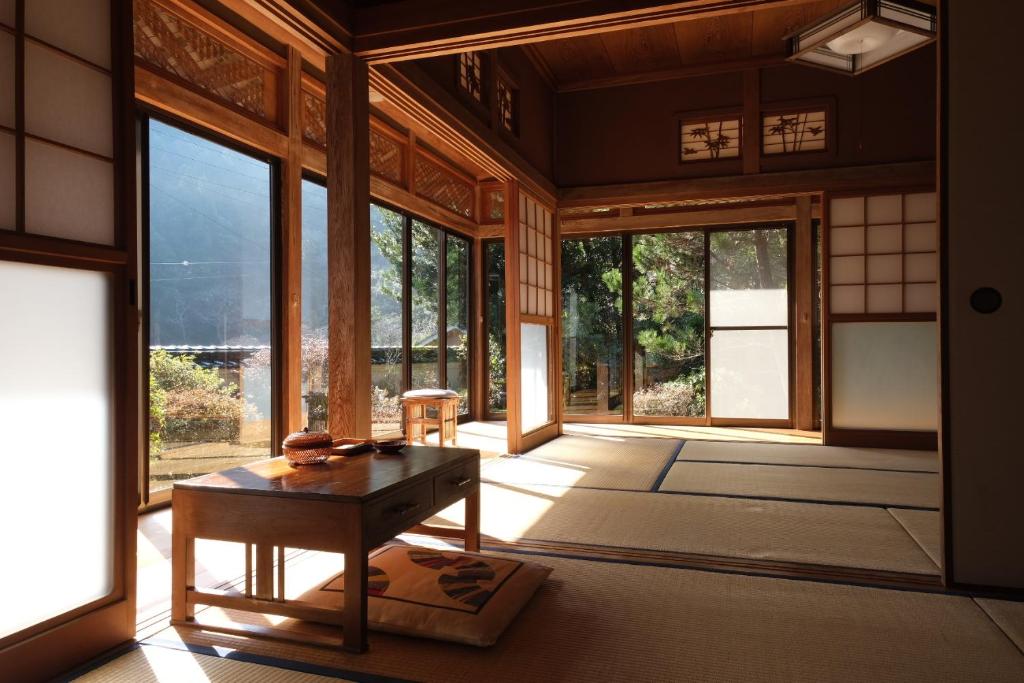 een kamer met een tafel en een aantal ramen bij Shimanto Riverside Hideaway in Shimanto