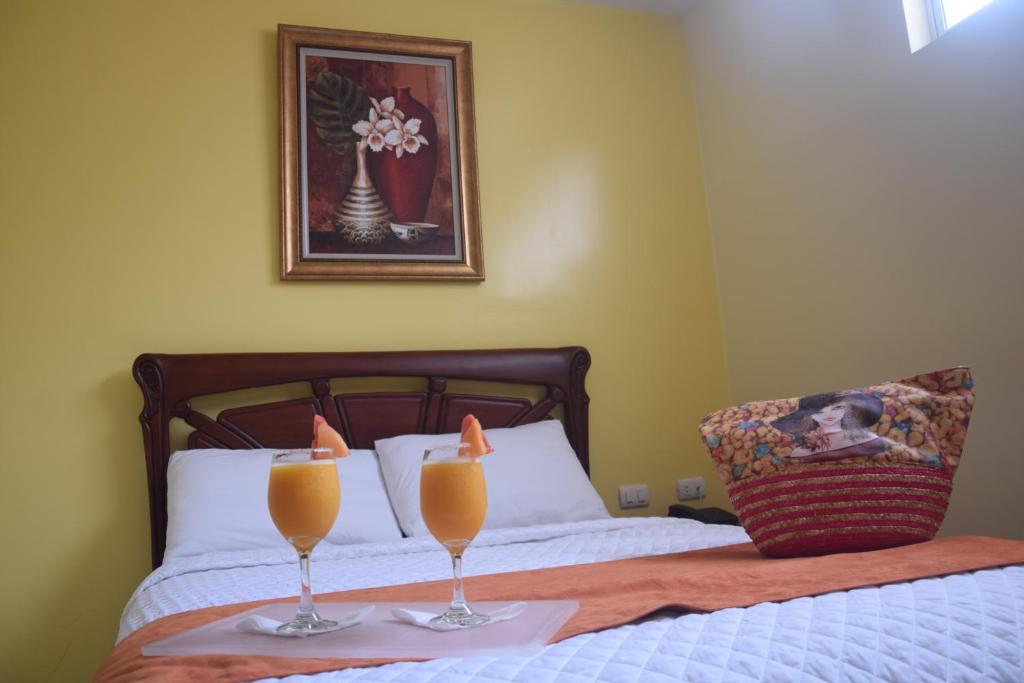 Hotel Cayapas Esmeraldas في إسمرالداس: كأسين من عصير البرتقال فوق السرير