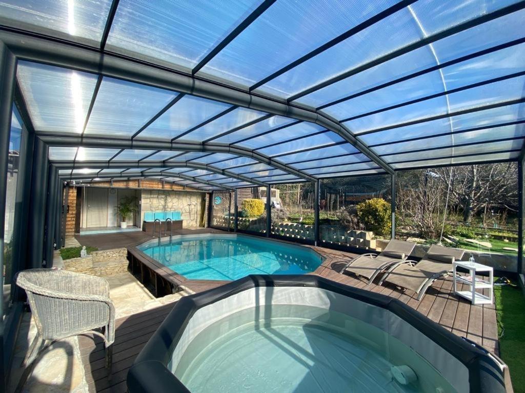 um pátio com uma piscina e um grande telhado de vidro em Chambre d hôtes AU CŒUR DES OLIVIERS em Marselha