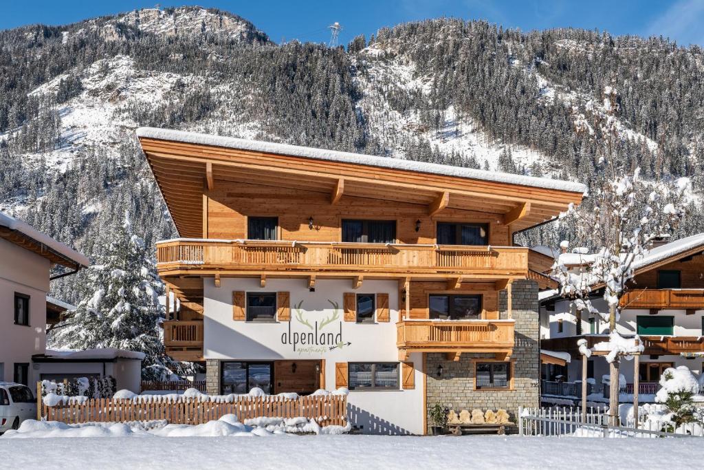 un edificio en la nieve frente a una montaña en Apart Alpenland en Mayrhofen