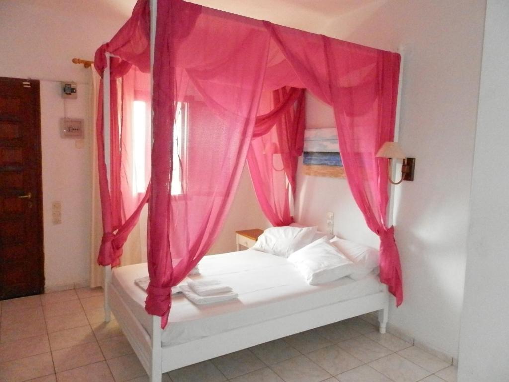 a bedroom with a bed with pink curtains at Aeolos Hotel Apartments in Gythio