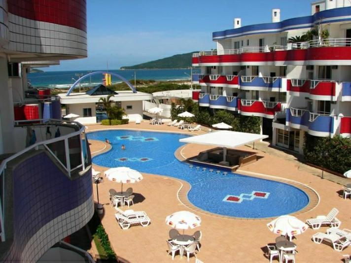 una piscina con sombrillas y sillas y un hotel en Holiday Ingleses Florianópolis, en Florianópolis