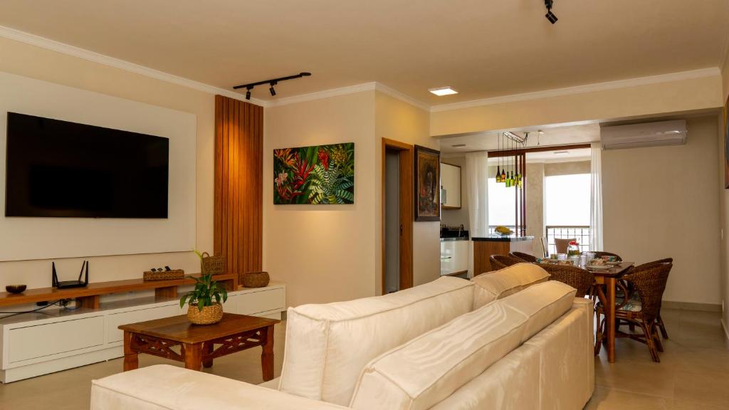 uma sala de estar com um sofá branco e uma mesa em Apartamento de Frente para o Mar no Itagua 01 em Ubatuba