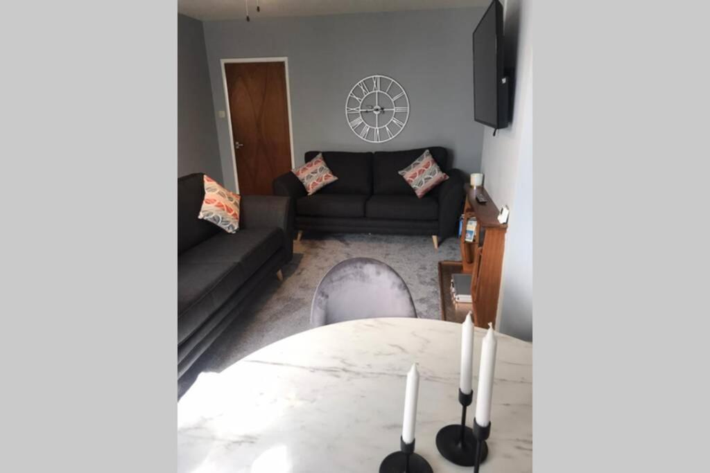 a living room with a black couch and a table at St Andrews Bungalow in Fife