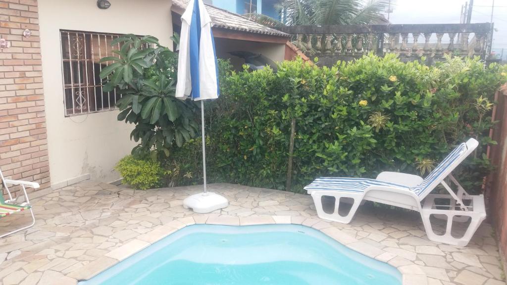 a pool with an umbrella and a chair and an umbrella and a table at Meu Cantinho in Itanhaém