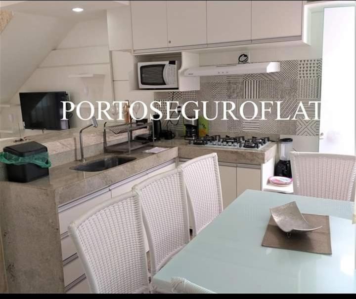 eine Küche mit einem Tisch und Stühlen sowie eine Küche mit einer Mikrowelle in der Unterkunft Vila dos diamantes flats de luxo lançamento in Porto Seguro