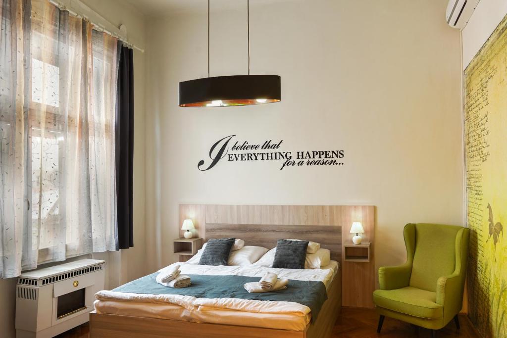 een slaapkamer met een bed en een groene stoel bij Pásti Centrál apartment. in Debrecen