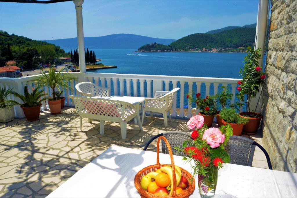 un tavolo con un cesto di frutta e fiori sul balcone di Apartments Okuka a Tivat