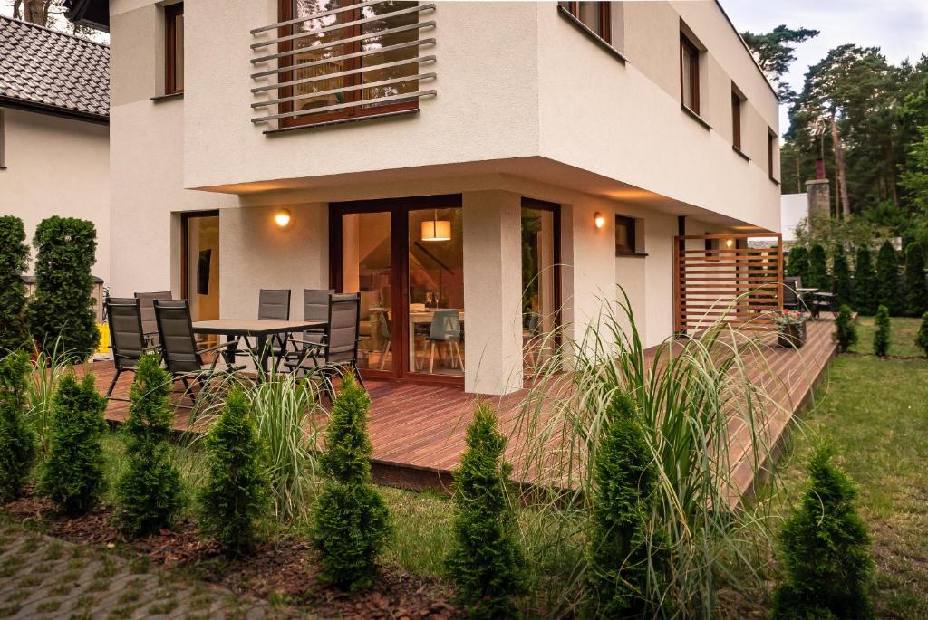 une maison avec une terrasse en bois et une table dans l'établissement NADMORSKI-DOM Pobierowo Summer-house, à Pobierowo