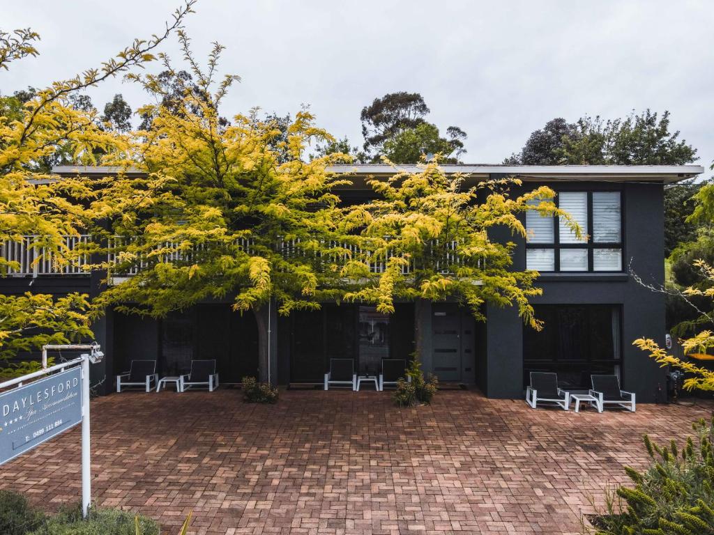 una casa con sillas y un árbol delante de ella en Daylesford Spa Accommodation, en Daylesford