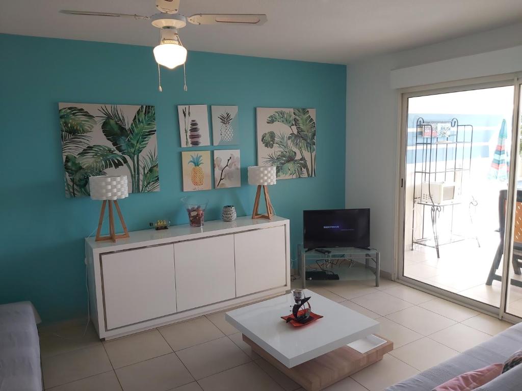 a living room with a white cabinet and a tv at Appartement face à la marina du marin martinique in Le Marin