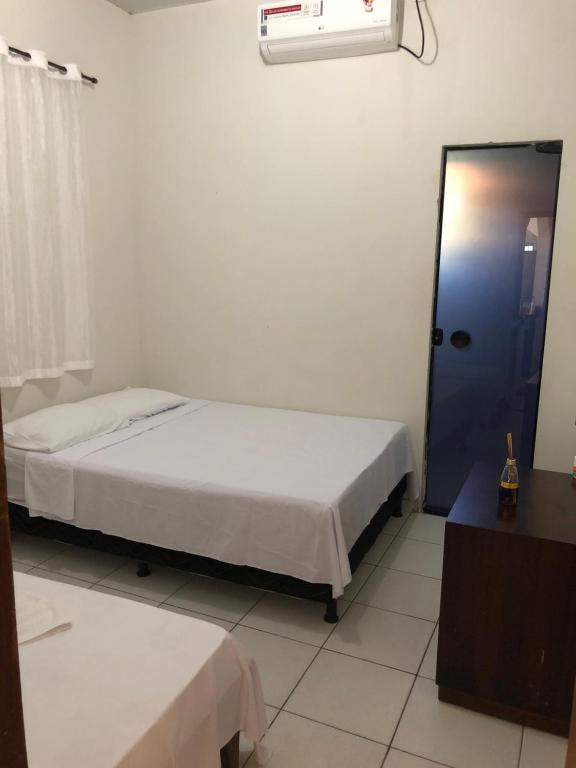 a bedroom with two beds and a blue door at Pousada Ambiente Familiar in Ponte Alta do Tocantins