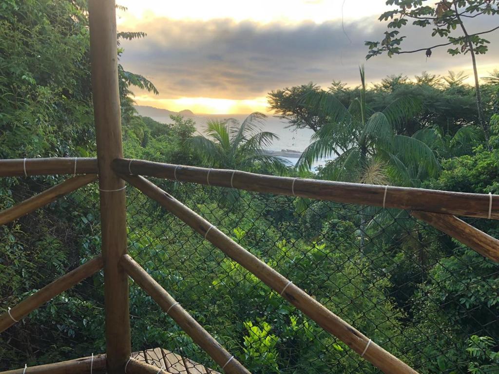 a view of the sunset from a wooden fence at Casa Mar e Montanha 2, deck com vista para o mar in Trindade