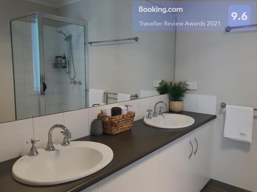 een badkamer met 2 wastafels en een spiegel bij Luxury 4BR Home with KING Bed Lakes Entrance in Lakes Entrance