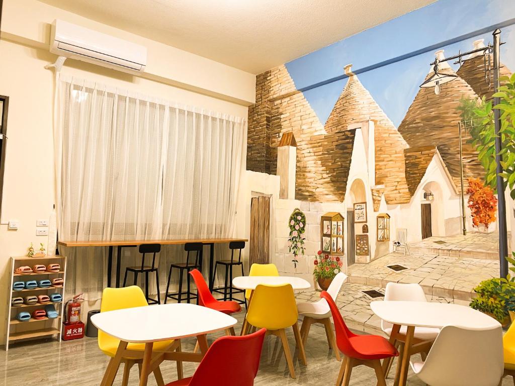 a restaurant with tables and chairs in front of a church mural at Mo Dou Homestay in Taitung City